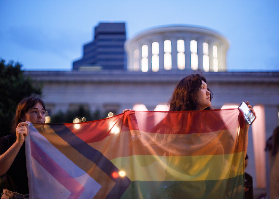 Transgender rights advocates holding a pride flag outside the Ohio Statehouse.