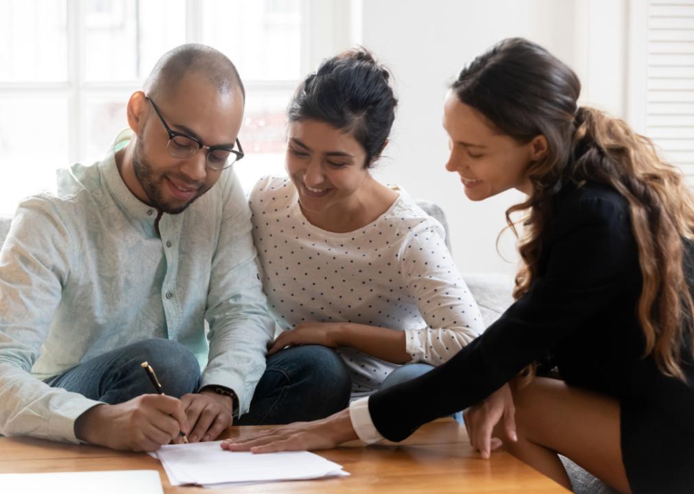 Real estate agent with couple signing contracts.