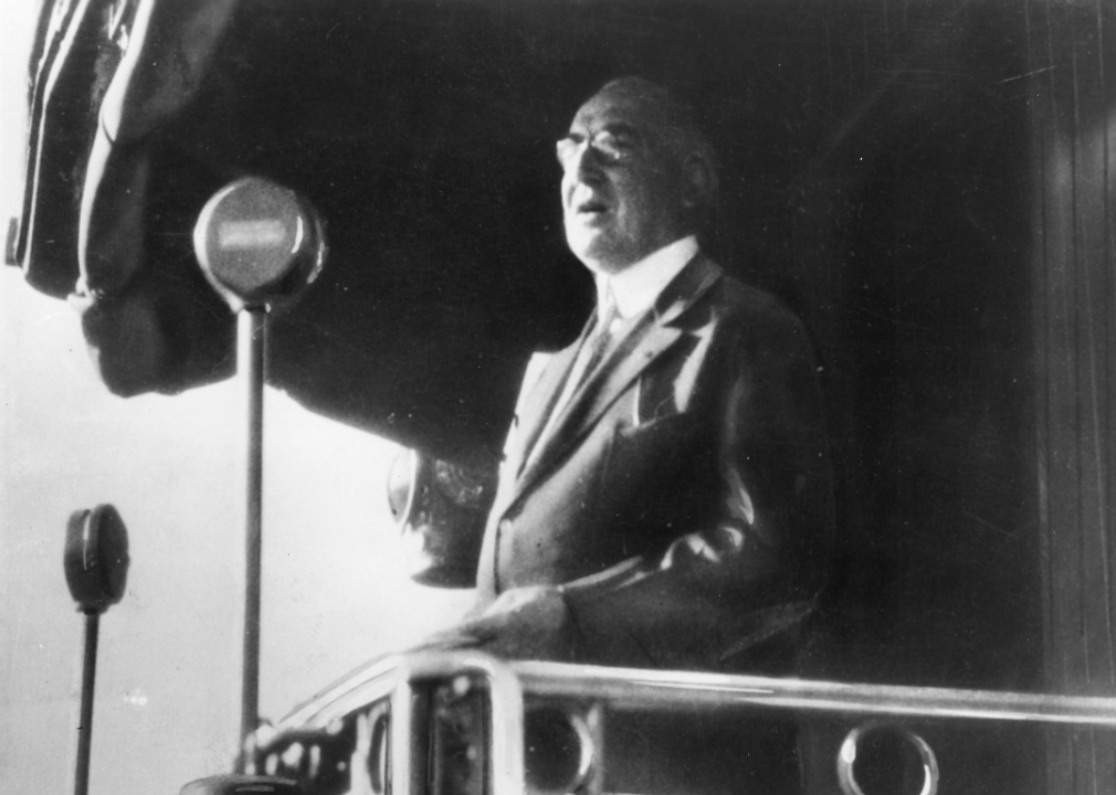 Warren G Harding speaks into microphones at a campaign stop.