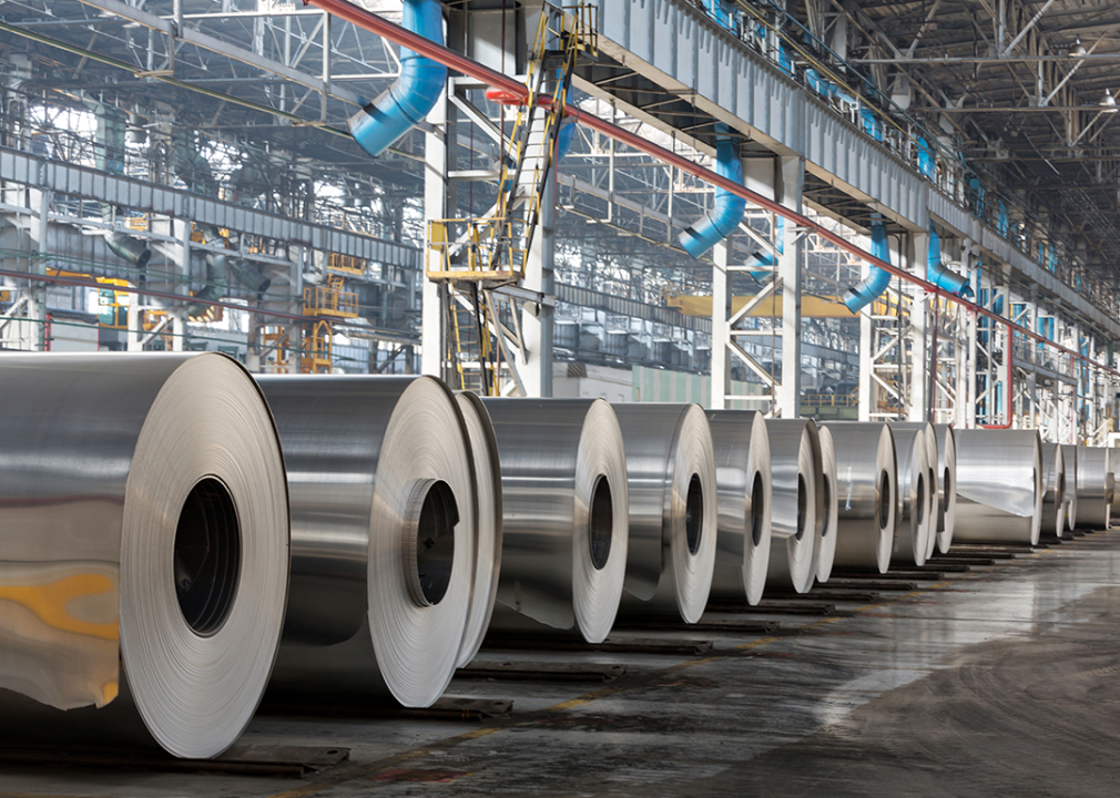 Row of rolls of aluminum lie in production shop of plant.