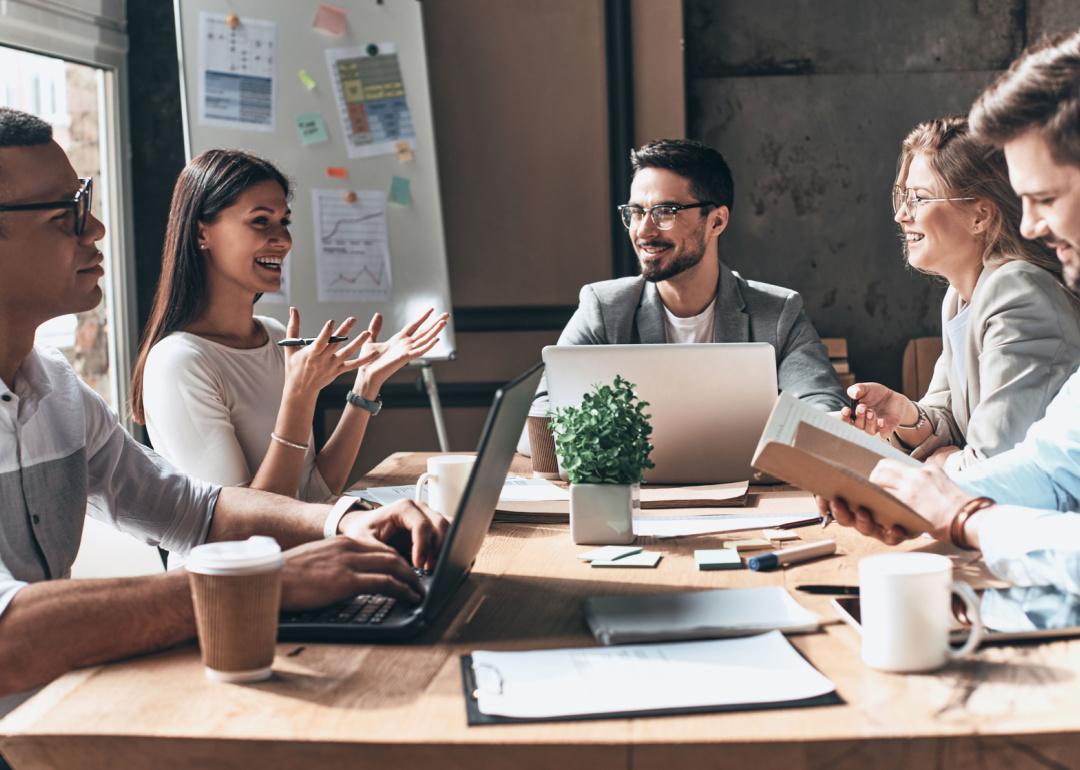 Group of five people in a business meeting at a conference table.