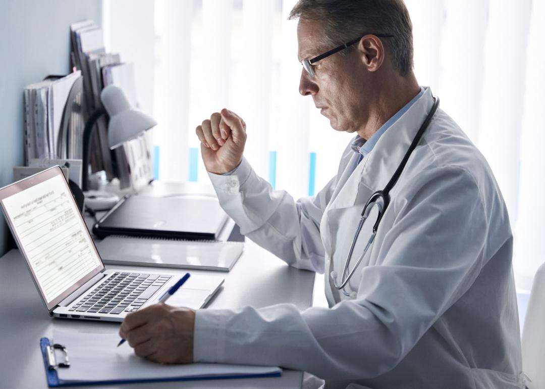 Doctor using laptop to enter records.