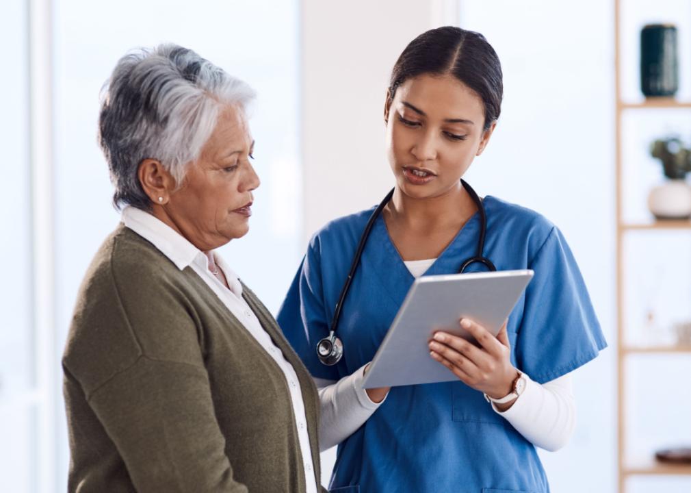 A medical professional reviewing information on tablet with a patient.