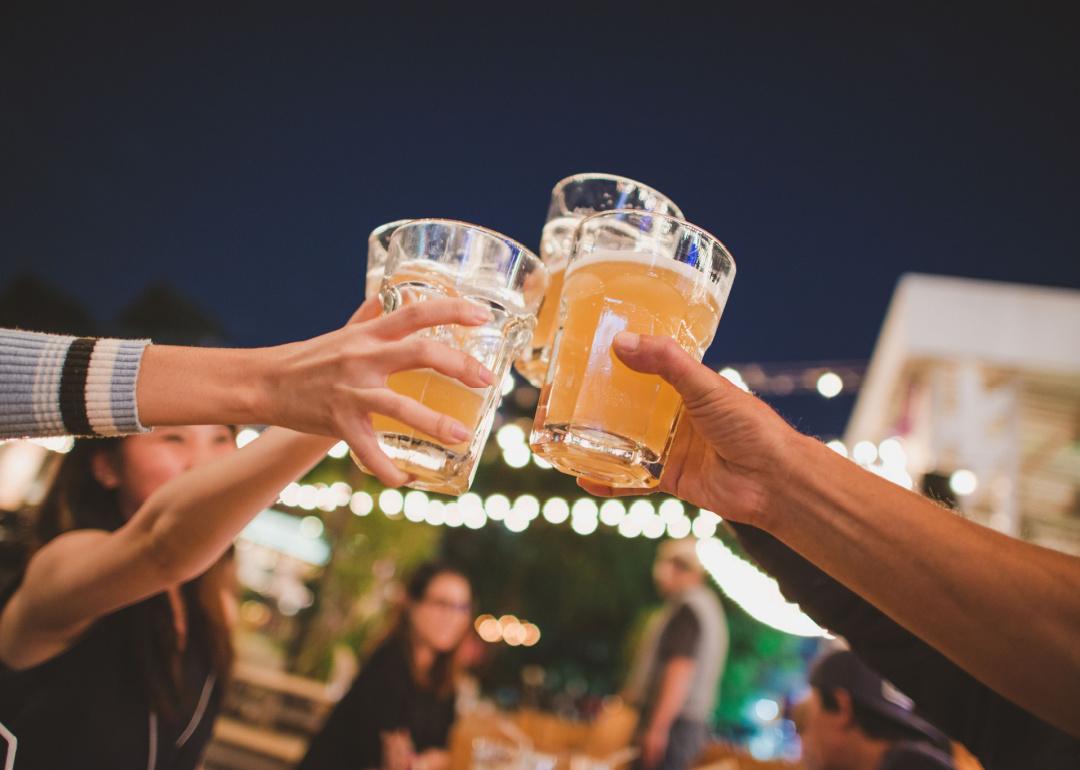 People raise beer glasses together outside.