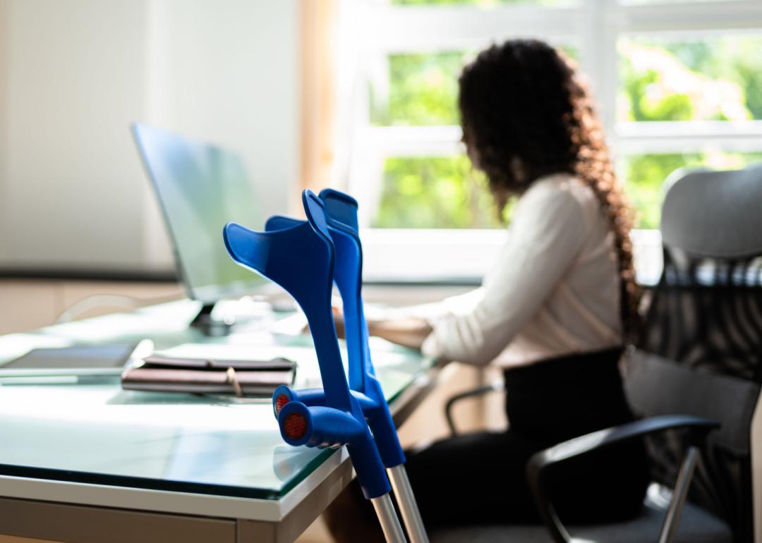 Worker with crutches at desk.