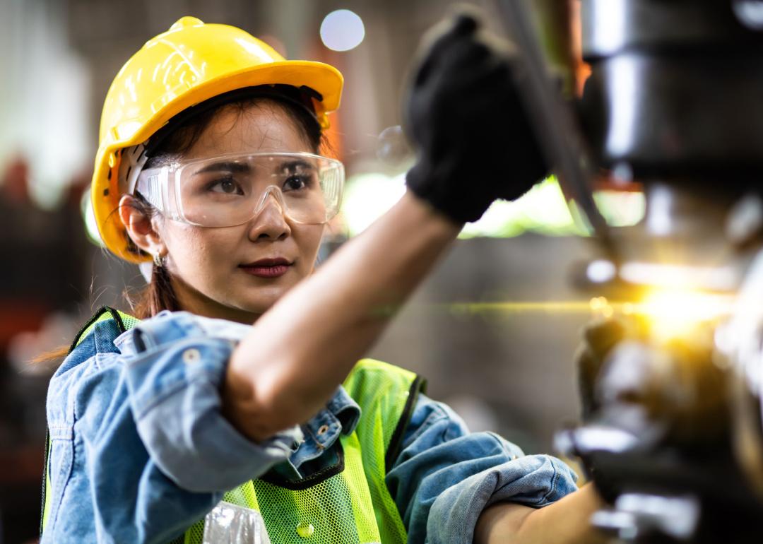 Woman wearing protective clothing working at industrial machine.