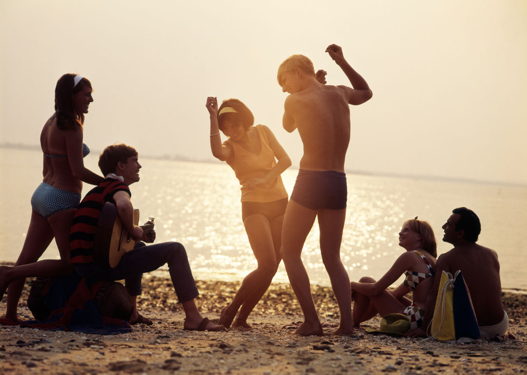 Group of friends dancing at a sunset beach party.