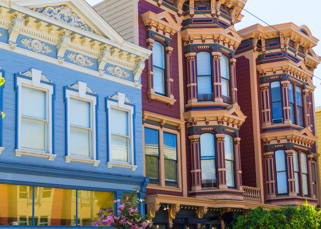Exterior of a row of colorful Victorian homes with intricate wood trim.