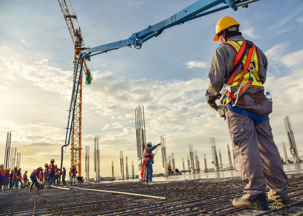 Manager watches construction workers pouring concrete.