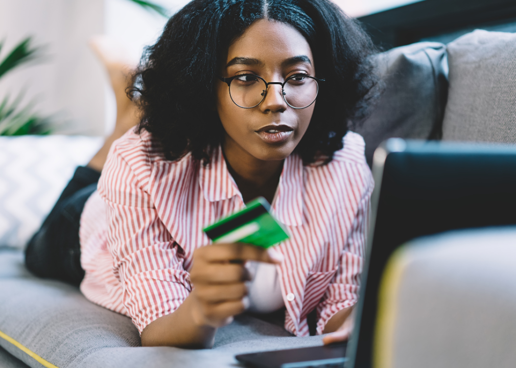 Woman on couch with laptop and debit card