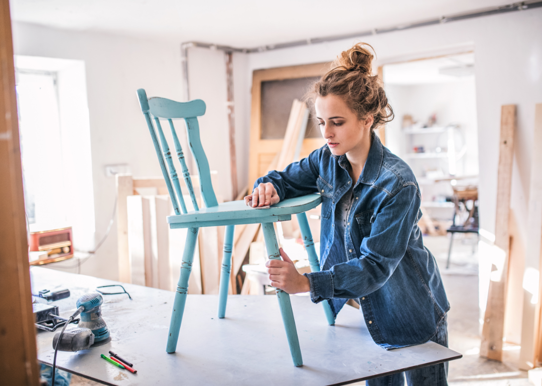 Person in workshop sanding vintage chair.