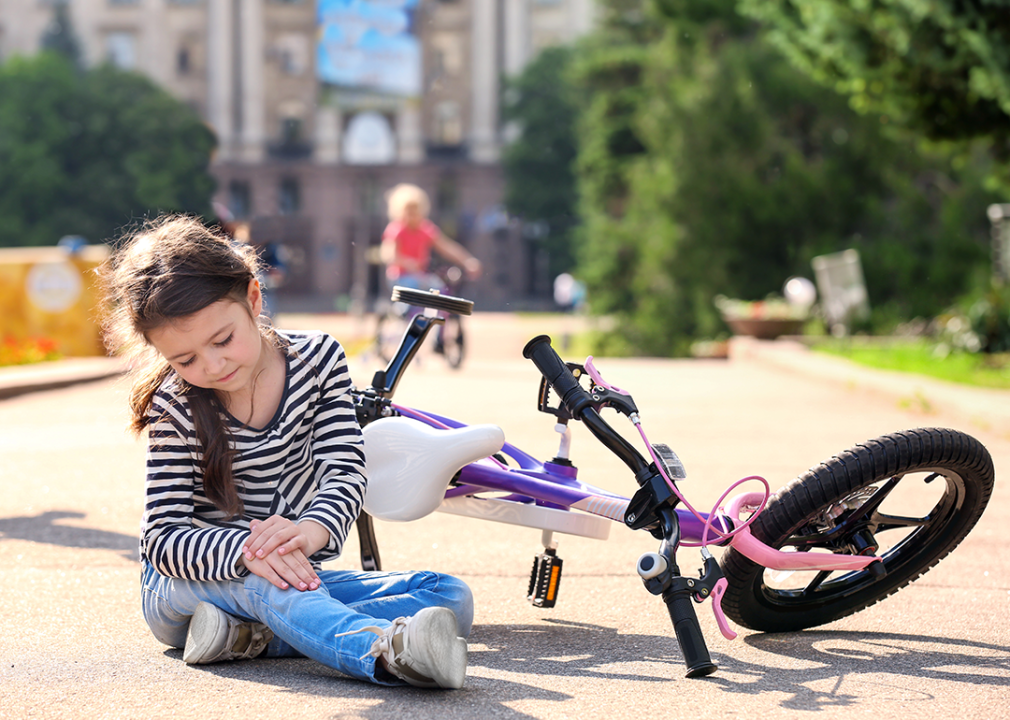 Girl holding knee after falling off her bicycle.