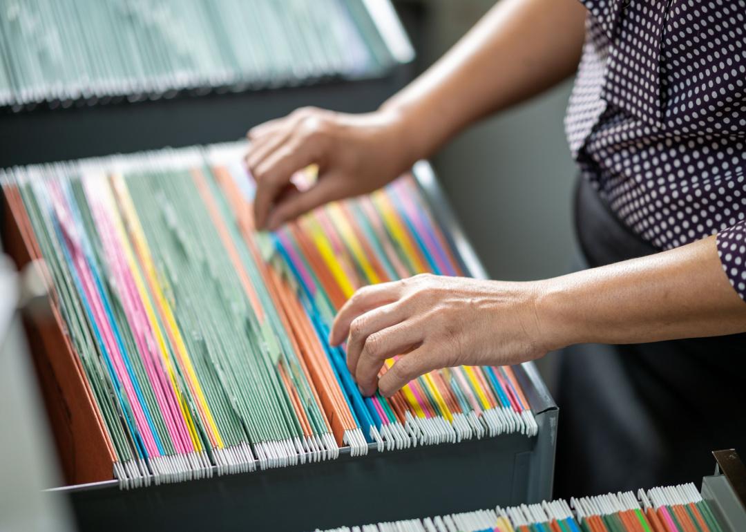 Person searching for documents in filing cabinet