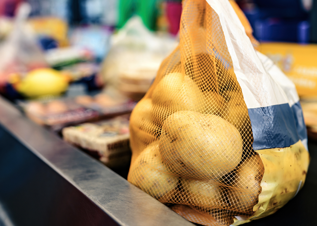 A bag of potatoes on the conveyor belt at the supermarket check out.