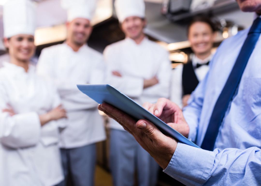 Restaurant manager using digital tablet in commercial kitchen.