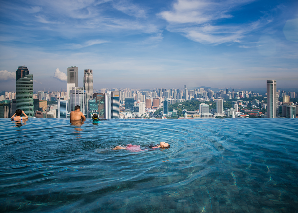 People swimming in Singapore rooftop infinity pool, looking out toward the city.