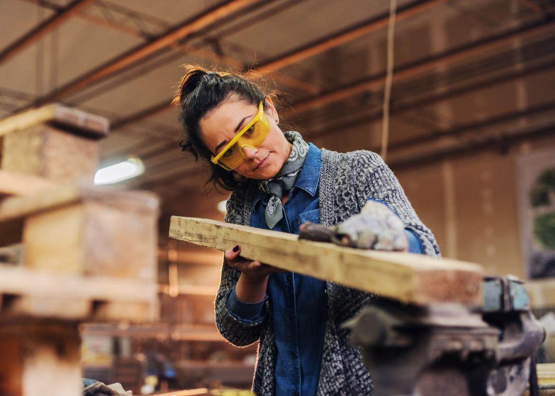 A woman carpenter choosing wood.