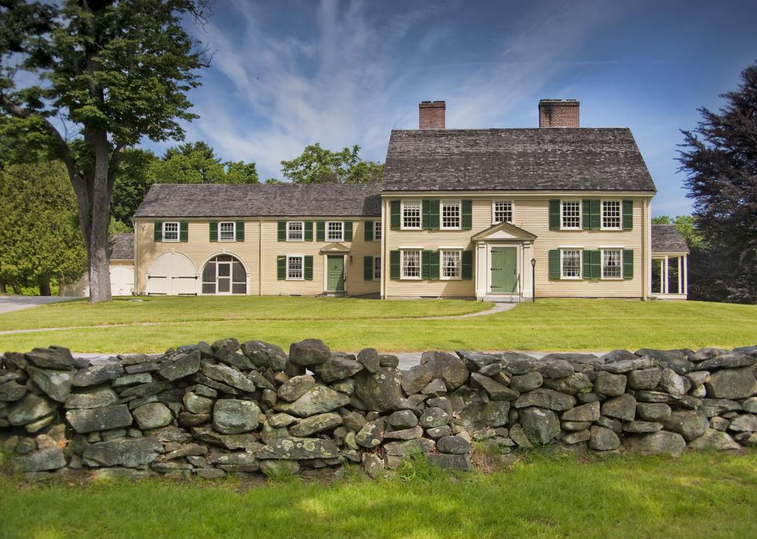 New England colonial home with stone wall.