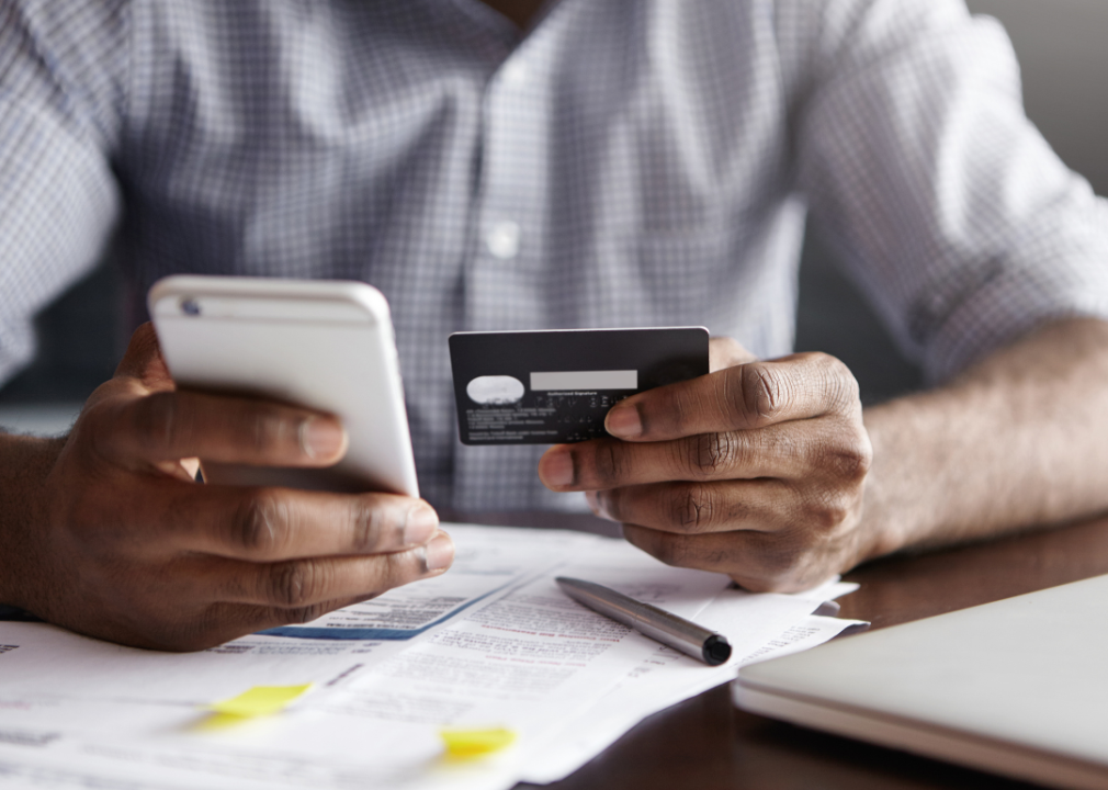 Close up male hands with credit card, smartphone and account statement