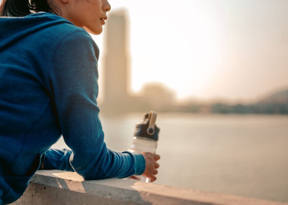 Woman pausing to drink water admiring city view