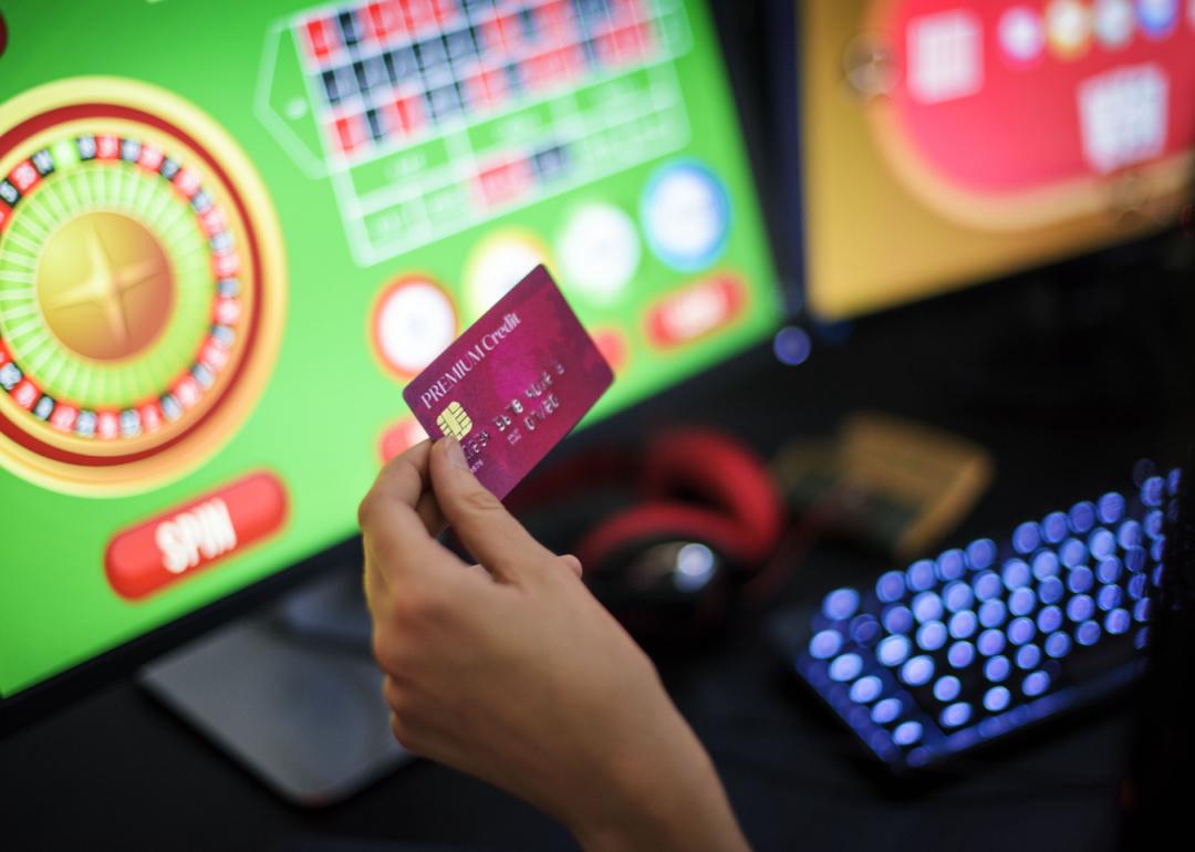Hand holding credit card playing online roulette.