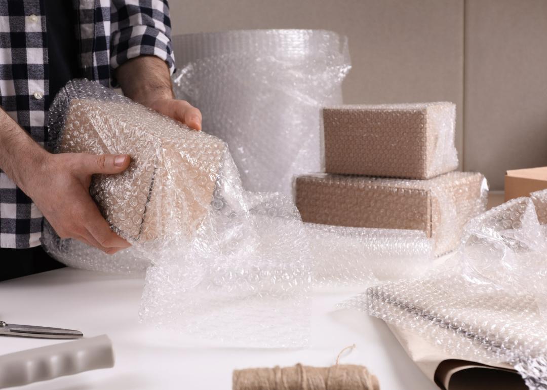 Person wrapping packages in bubble wrap