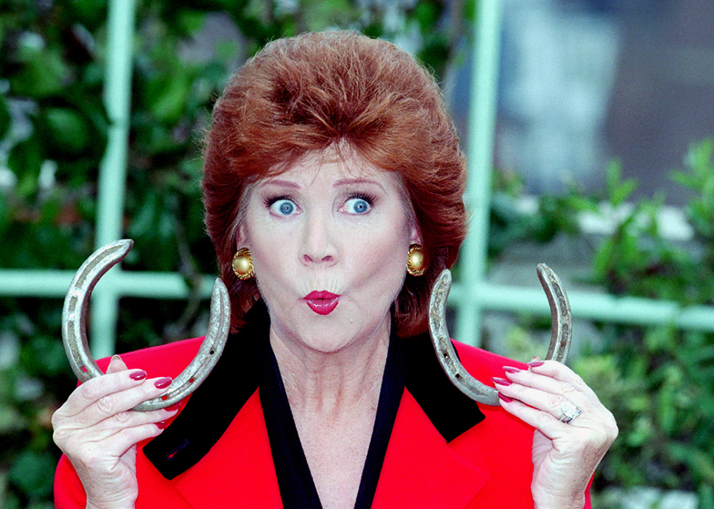Cilla Black holding a pair of lucky horseshoes.