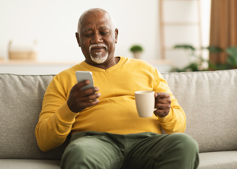 Older man sitting on couch looking at phone.