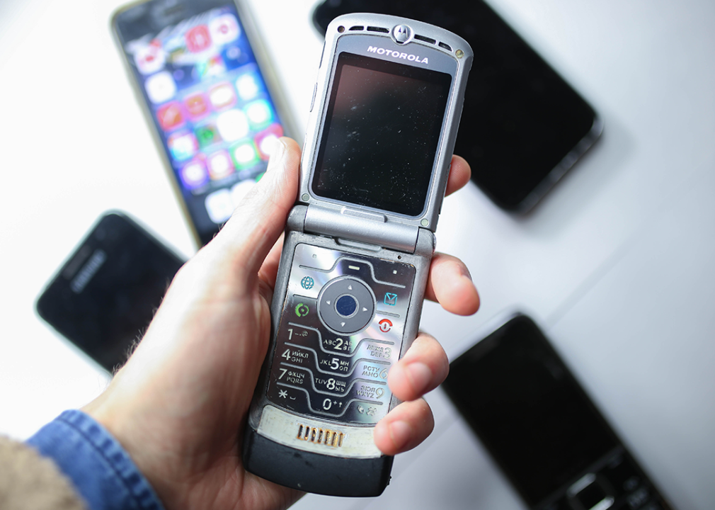 A hand holds a Motorola RAZR V3 phone.