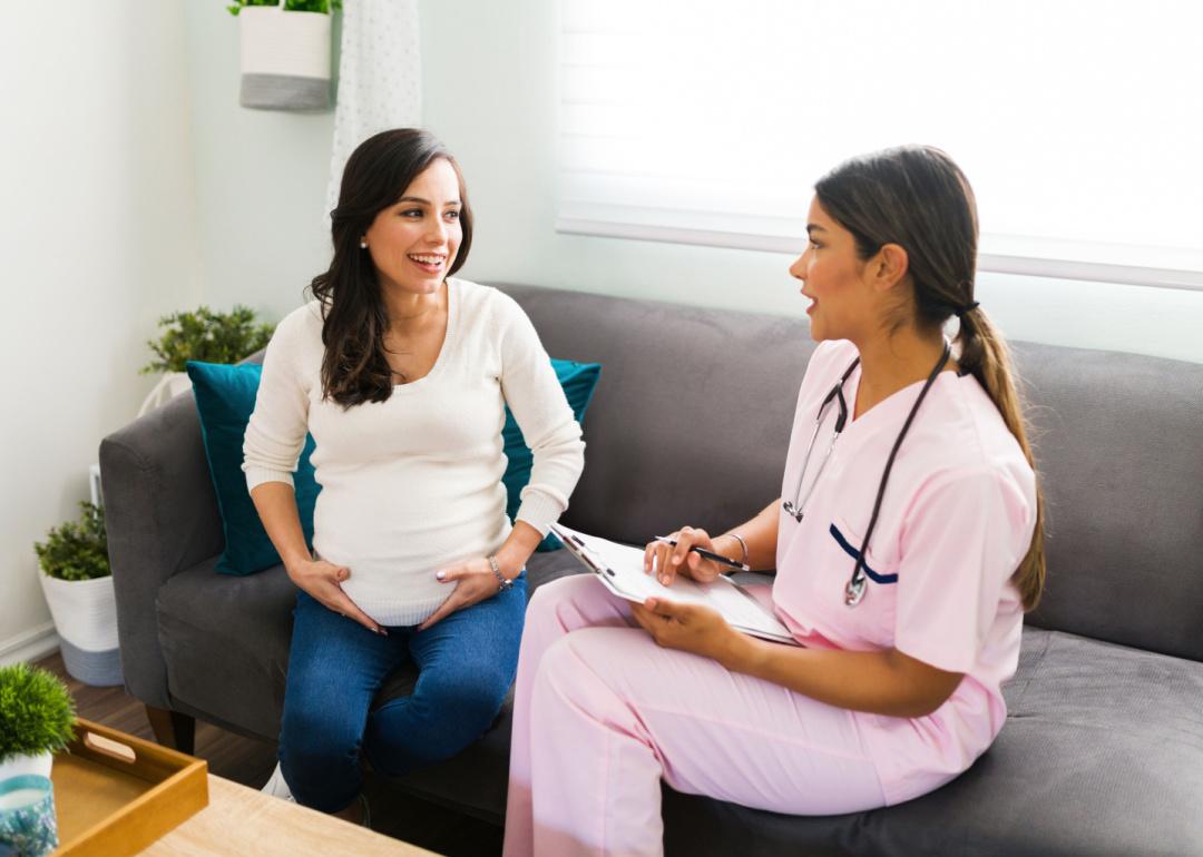 Midwife nurse talking to pregnant patient.