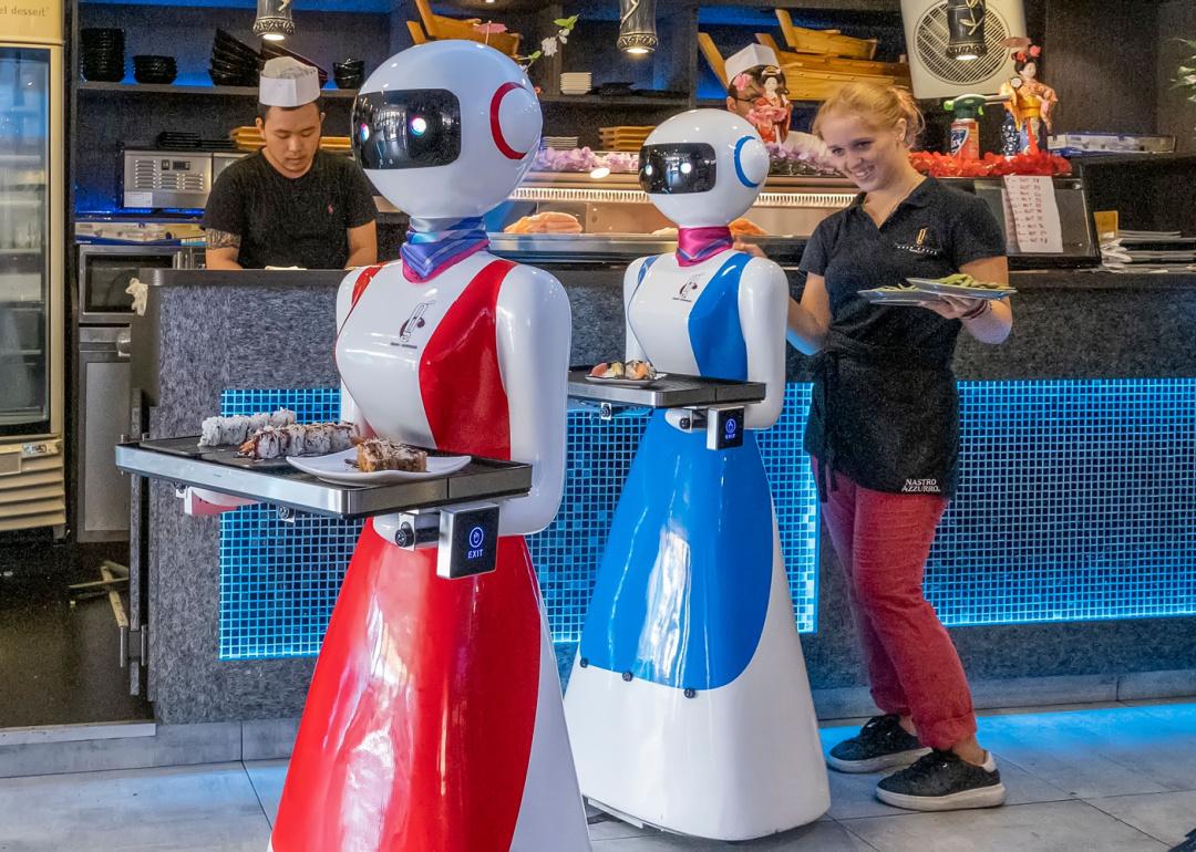 Waiter robots bring food to table at restaurant.