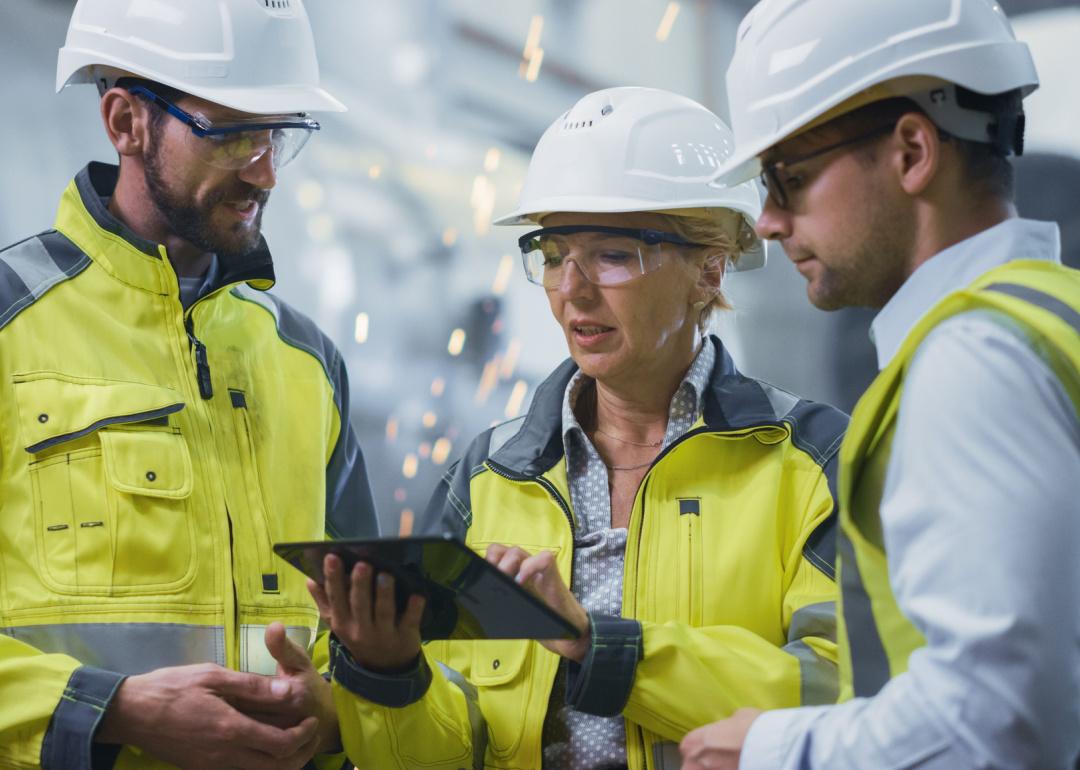 Three factory engineers discussing work wearing hardhats.