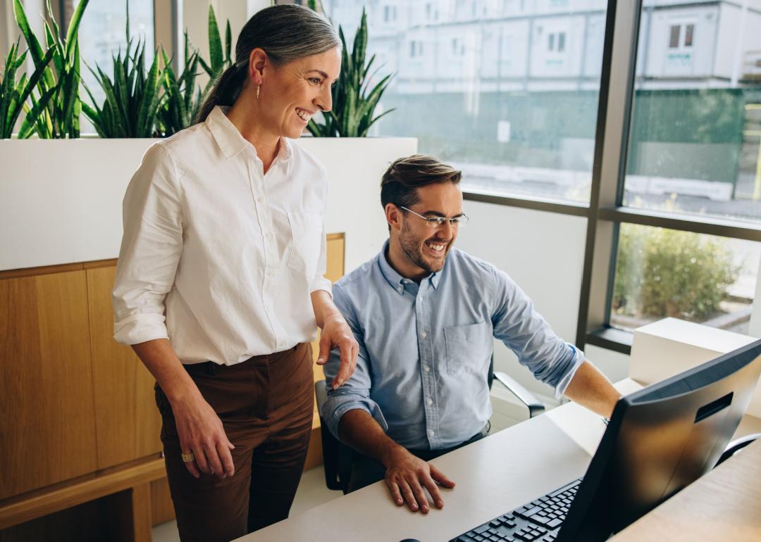 Coworkers behind desk looking at computer.