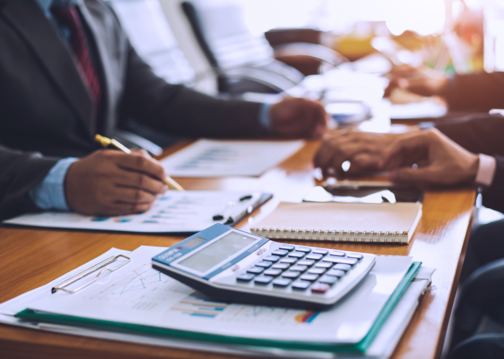 Cropped view of professionals reviewing paperwork with calculator