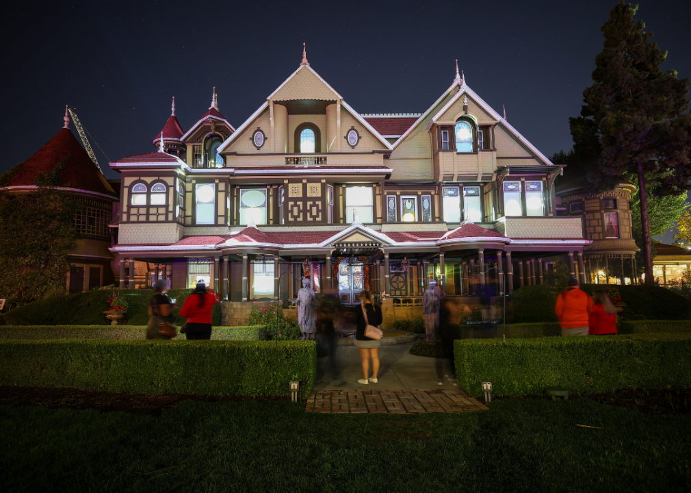 People standing outside the Winchester Mystery House at night.