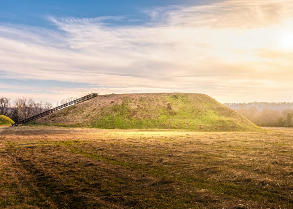 Sunset on Etowah Indian Mounds Historic Site, an open field with a mound and a wooden staircase/ramp leading up to it.