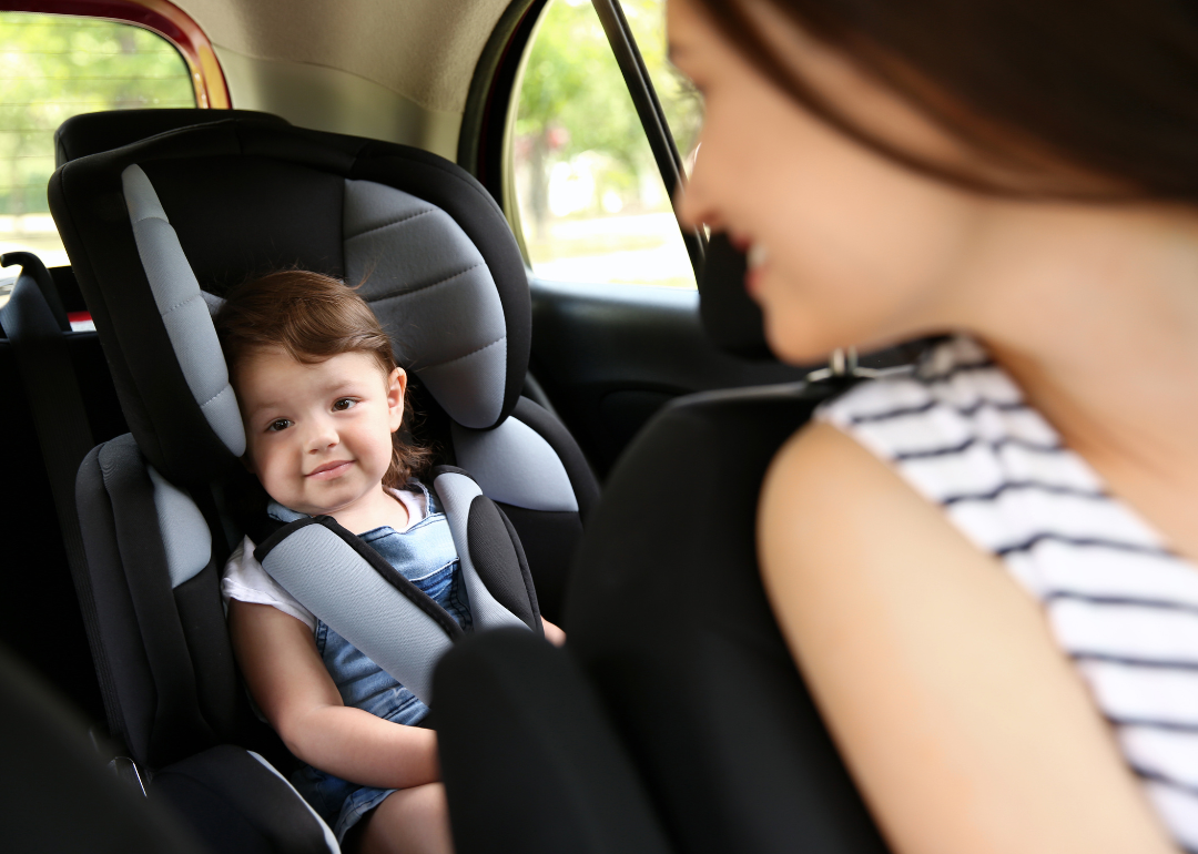 Mother looks over shoulder at child in rear car safety seat