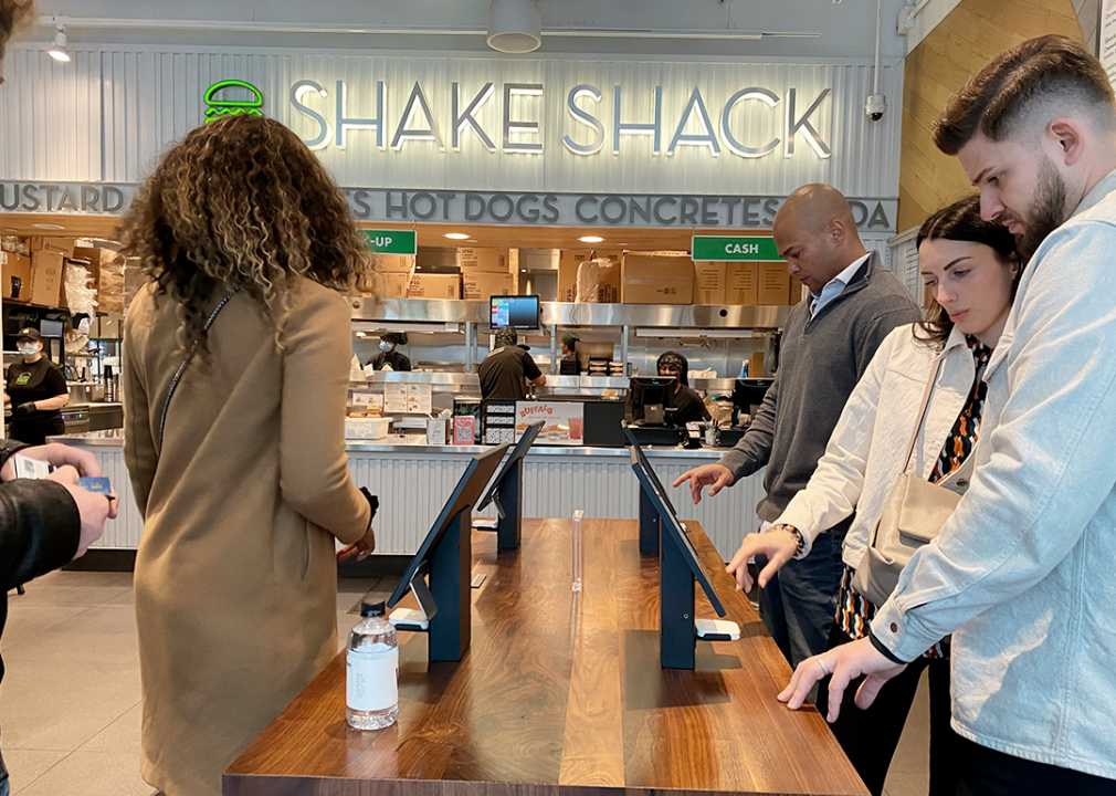 Customers using Shake Shack self-service ordering kiosks.