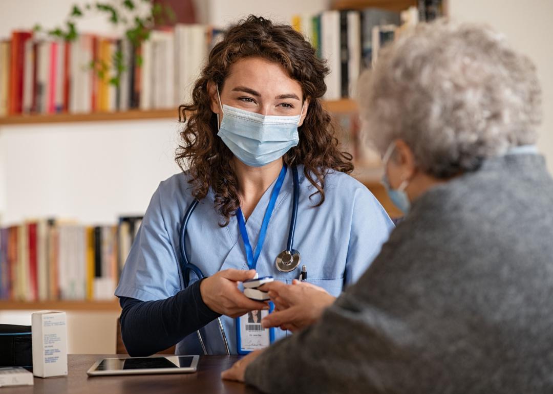 Nurse checking oximeter on senior patient.