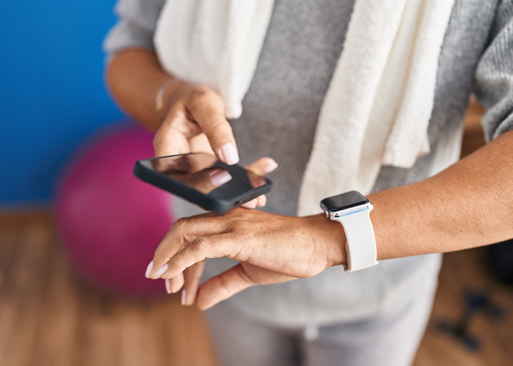 Woman checking phone and watch after exercising.