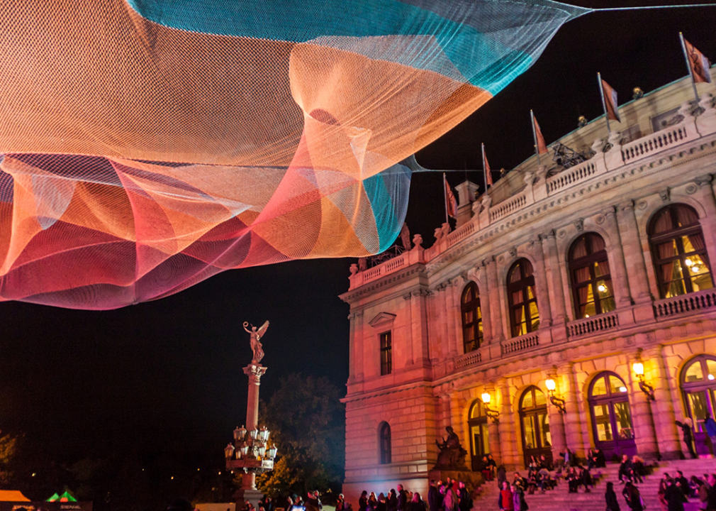 A colorful light installation next to the Rudolfinum building at night.