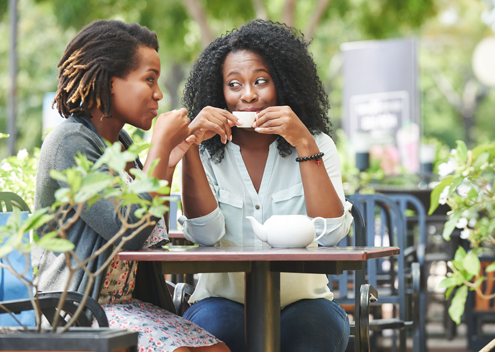 Women drinking tea and gossiping in outdoor cafe.