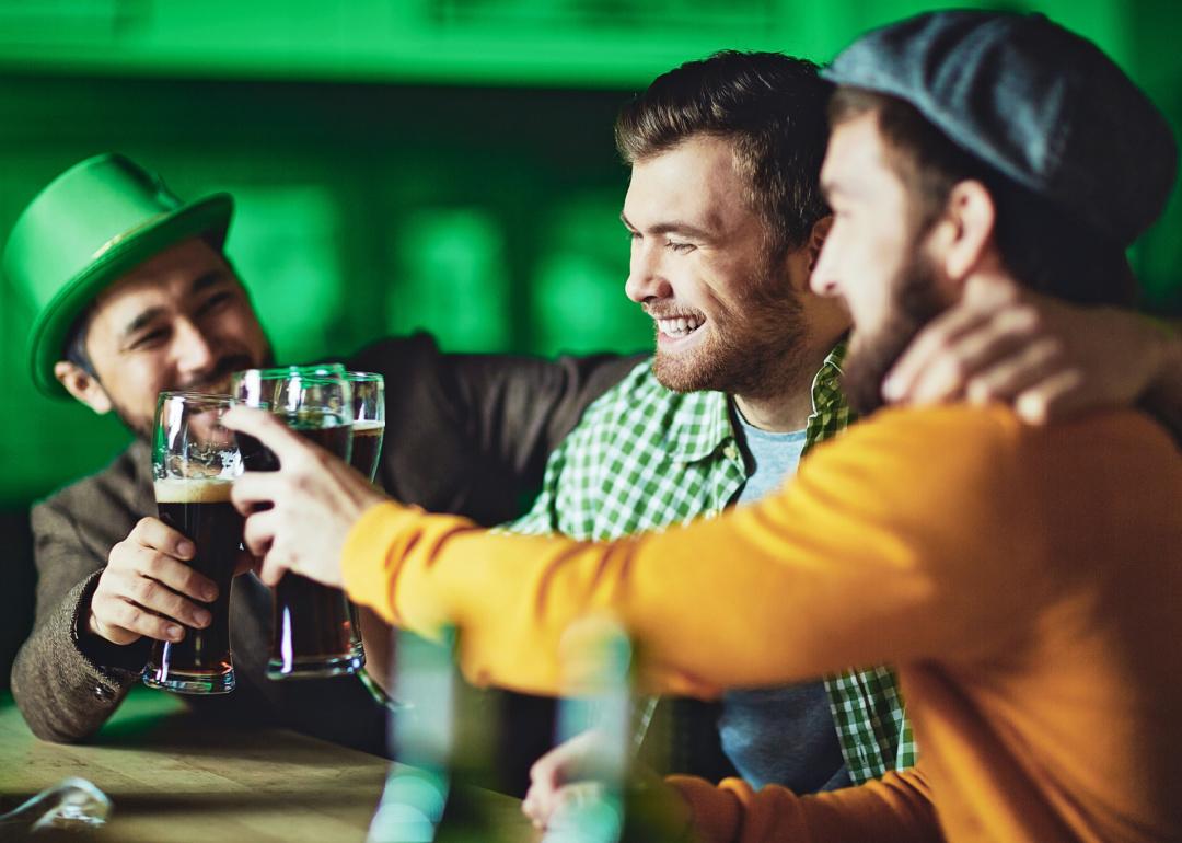 Three male friends toasting with beer in bar during St. Patrick