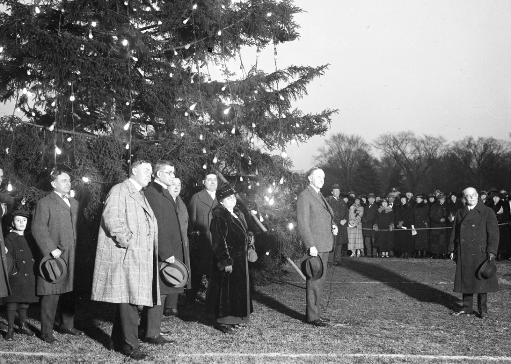 Calvin Coolidge and group pose in front of Christmas tree.