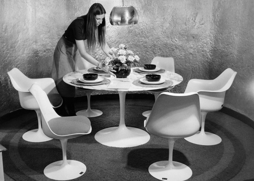 Woman standing with Eero Saarinen pedestal table and chairs.