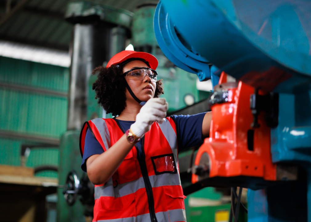 Female worker wearing safety equipment at lathe machine