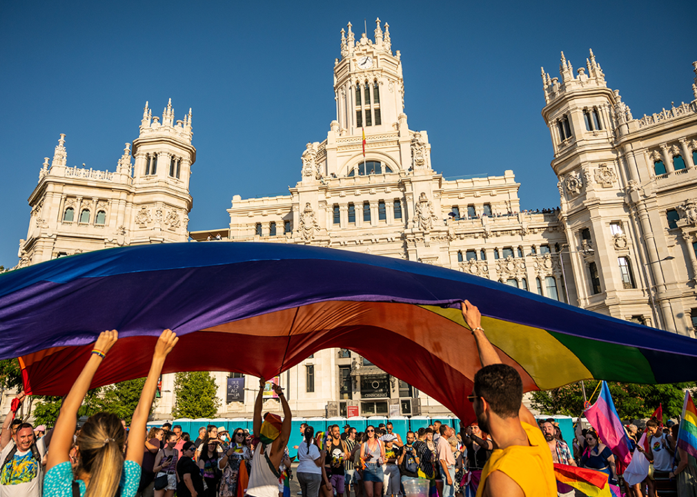 People carry a large rainbow flag as they pass by the City Council in Madrid.