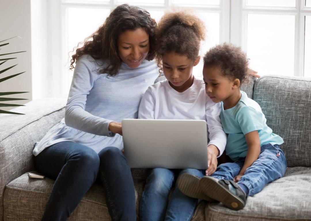 Mother and two children using laptop computer at home