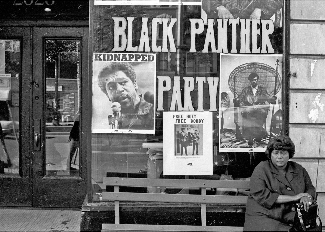 A woman sits on a bench outside the Black Panther office in Harlem.
