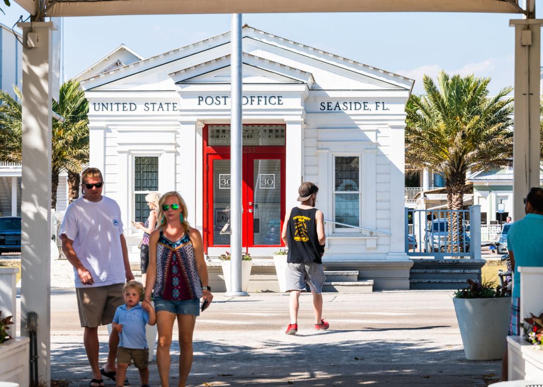 People walk in front of post office building in Seaside.